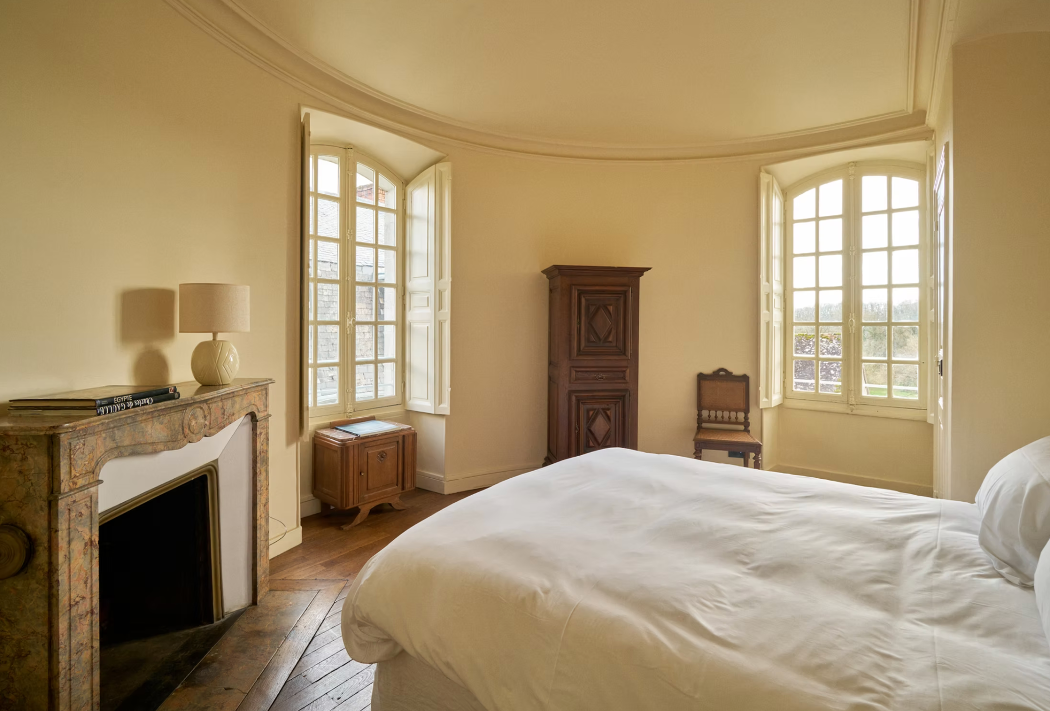 A château bedroom with curved walls and a marble fireplace